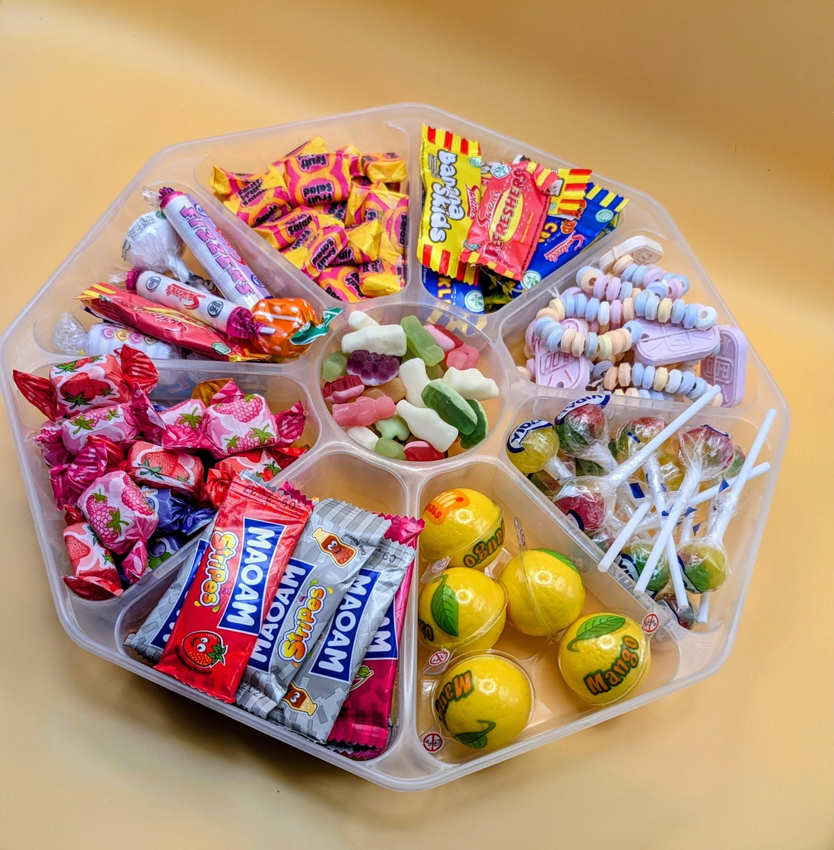 Sweet Feasts Candy Boards assorted retro sweet platter in a clear tray featuring fruit chews, lollipops, and gummies.